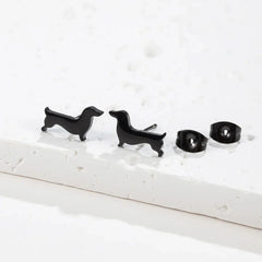 Black dachshund stud earrings on a stone slab with their butterfly backs