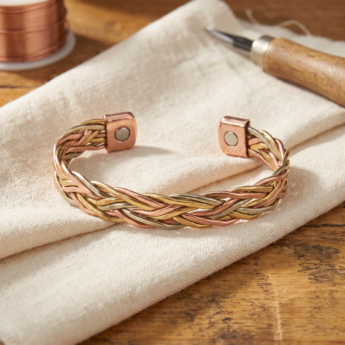 Braided copper cuff bracelet woven from copper, gold-tone and silver-tone wire with flat capped ends