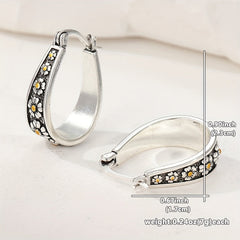 Brushed silver-tone oval hoop earrings with small gold-tone daisy motifs