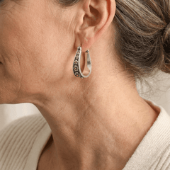 Brushed silver-tone oval hoop earrings with small gold-tone daisy motifs