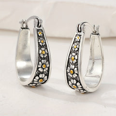 Brushed silver-tone oval hoop earrings with small gold-tone daisy motifs