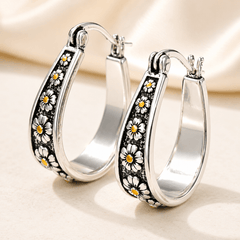 Brushed silver-tone oval hoop earrings with small gold-tone daisy motifs