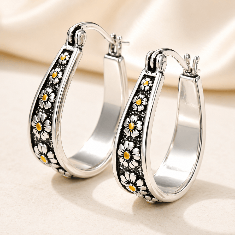 Brushed silver-tone oval hoop earrings with small gold-tone daisy motifs