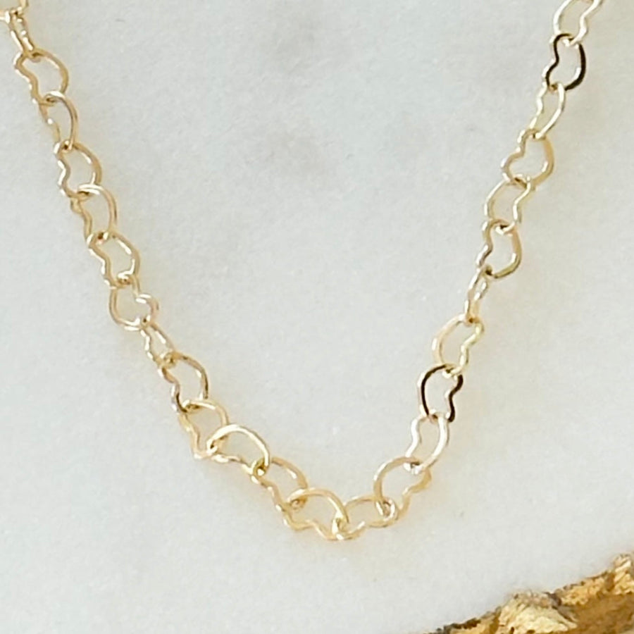 Close view of the open heart-shaped links of the gold-tone chain