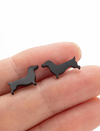 Dachshund stud earrings in black tone resting on fingers