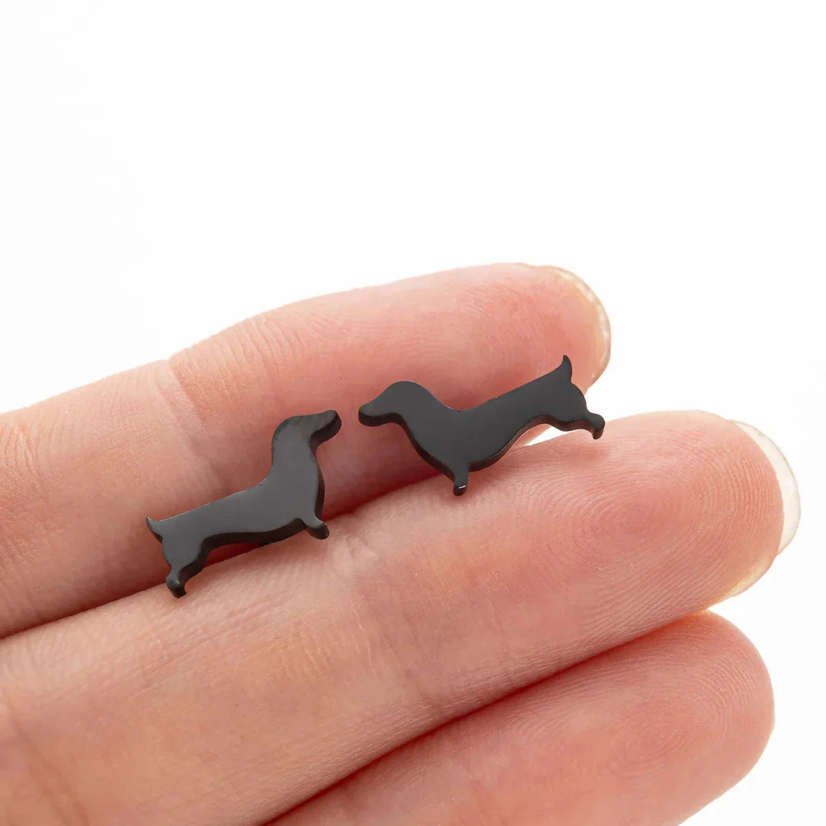 Dachshund stud earrings in black tone resting on fingers