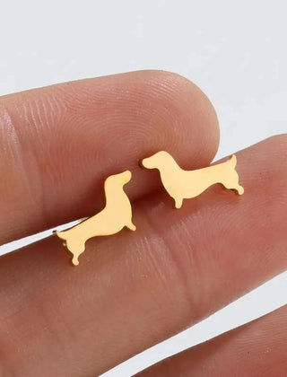 Dachshund stud earrings in gold tone resting on fingers