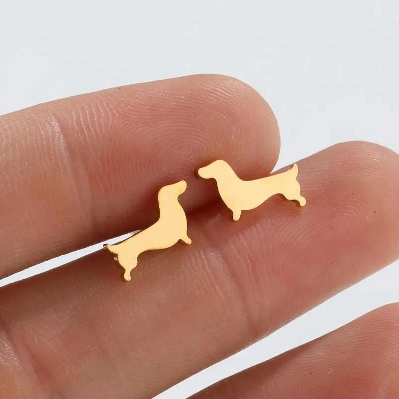 Dachshund stud earrings in gold tone resting on fingers