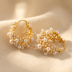 Gold-tone hoop earrings covered in clusters of small cream faux pearls