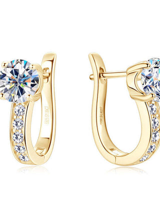 Gold-tone huggie hoop earrings with a large claw-set clear stone and a row of smaller stones down the band
