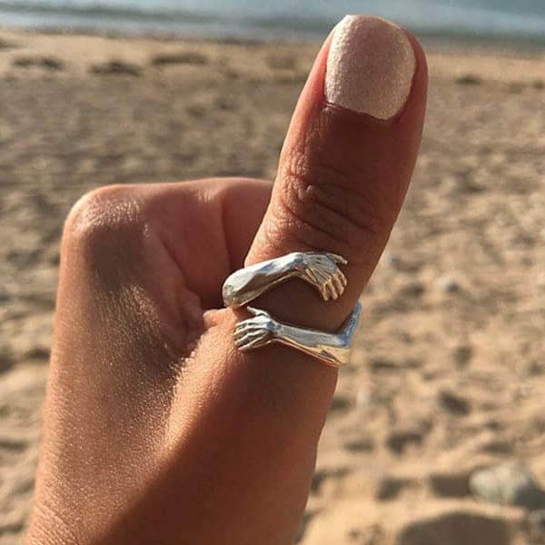 Hug ring worn on a finger, showing how the two arms overlap
