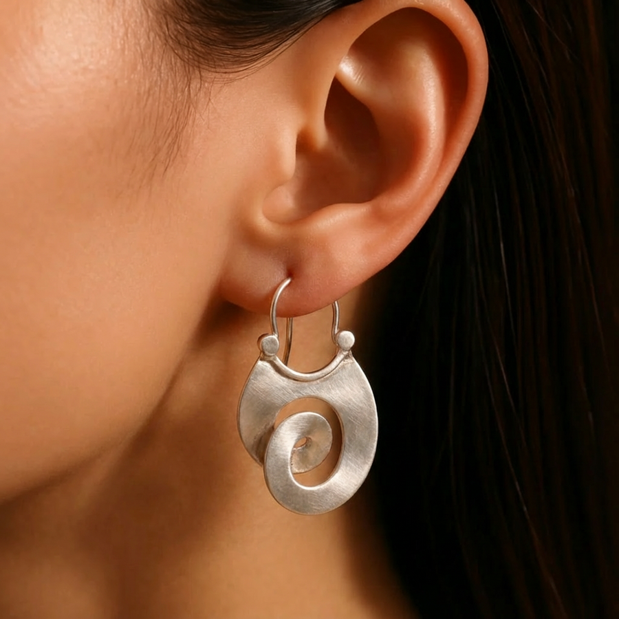 Large brushed silver-tone spiral disc earrings on a dark leather cord