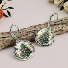 Pair of Christmas tree drop earrings resting on driftwood