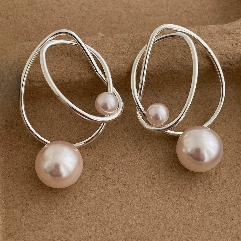 Pair of silver-tone wire loop earrings with a small pearl on the wire and a larger pearl hanging below