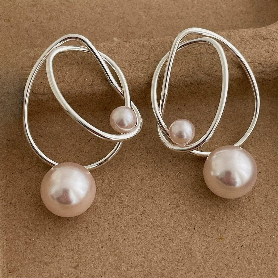 Pair of silver-tone wire loop earrings with a small pearl on the wire and a larger pearl hanging below