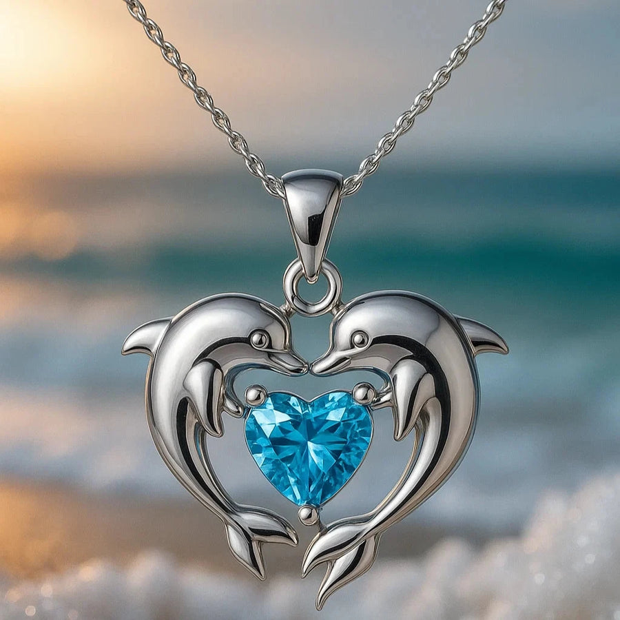 Silver-tone dolphin necklace with two dolphins forming a heart around a blue heart-cut stone