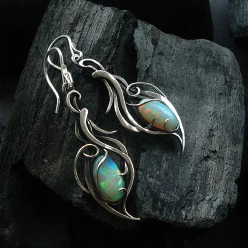 Silver-tone opal drop earrings with an oval cabochon set into an openwork leaf and swirl frame