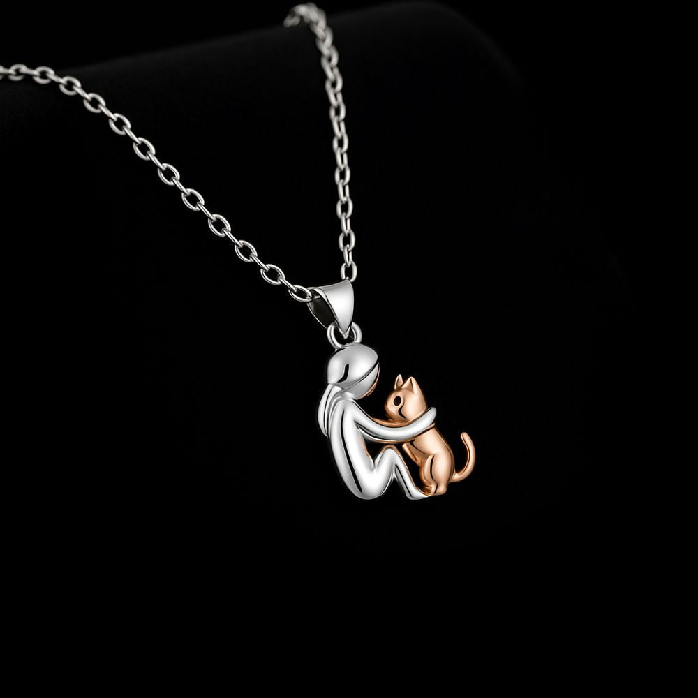 Silver-tone pendant of a seated figure hugging a rose gold-tone cat, on a fine cable chain