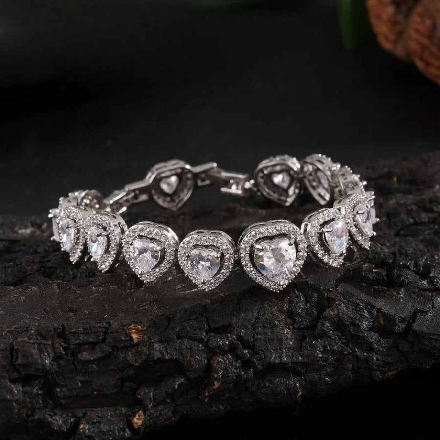 Silver-tone tennis bracelet with a line of heart-cut clear stones, each in a halo of smaller stones