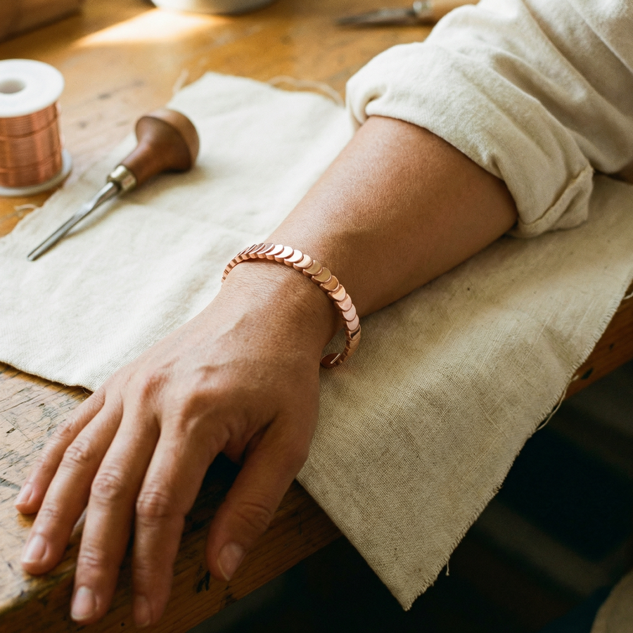The copper scale cuff worn on the wrist, showing how the discs curve around