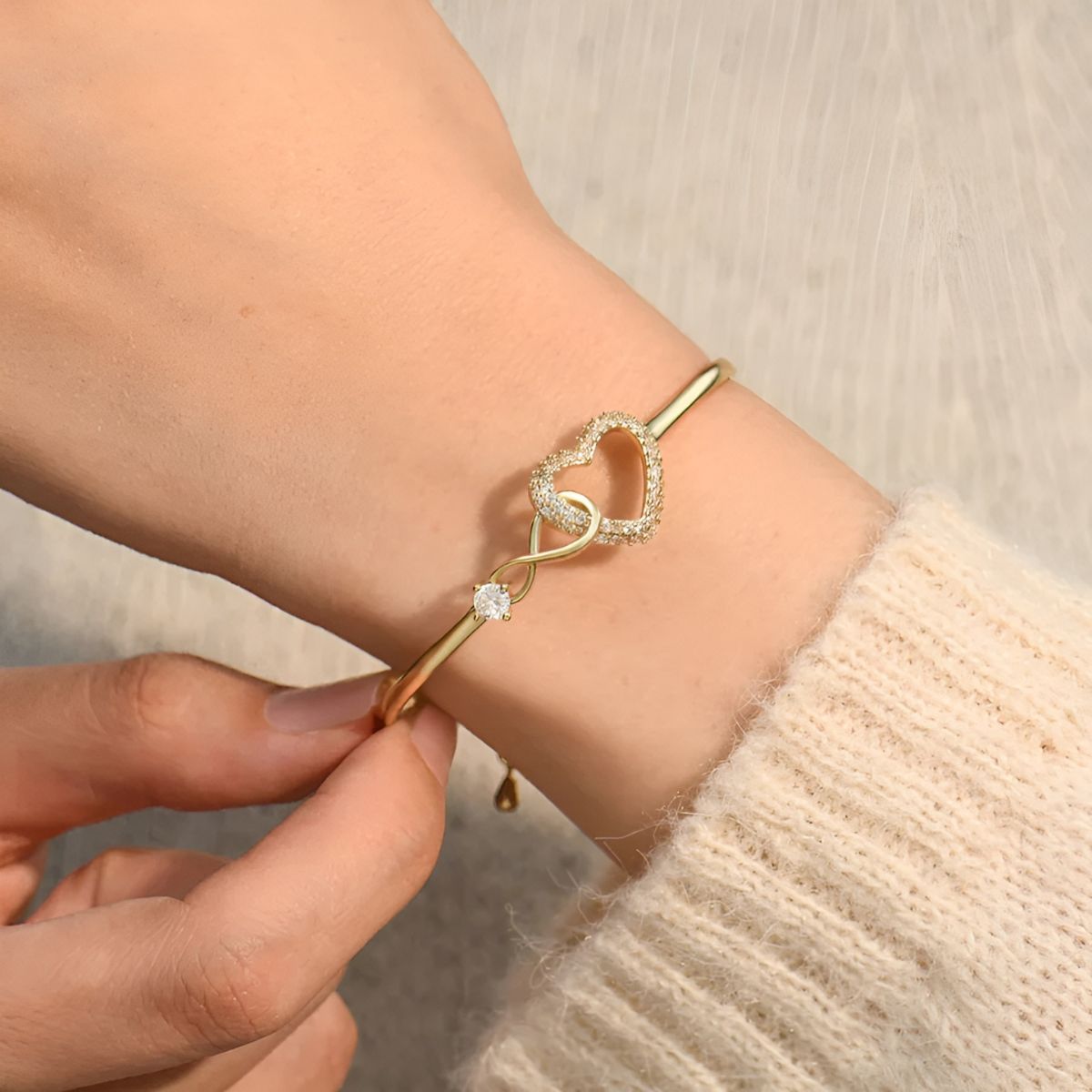 The gold-tone bangle being adjusted on the wrist