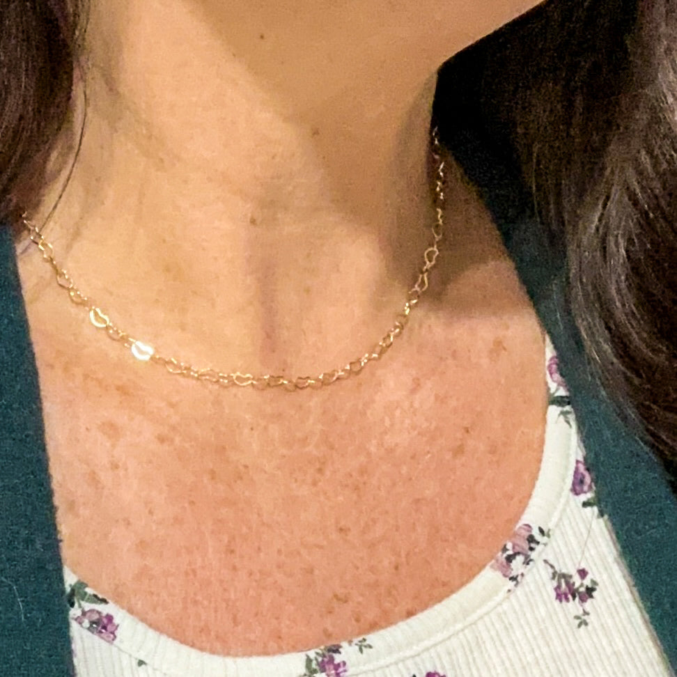 The heart chain necklace worn at choker length on the collarbone