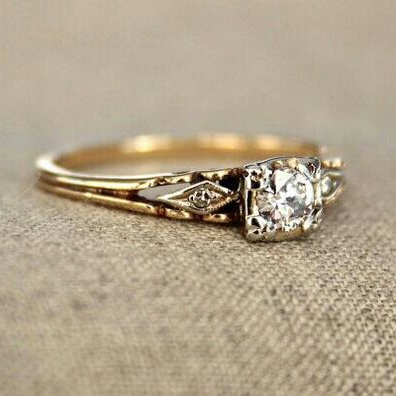 Vintage-style gold-tone promise ring with a clear faceted stone raised in a square four-claw setting